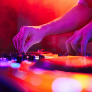 Close up of DJ hands on dj console mixer during concert in the club